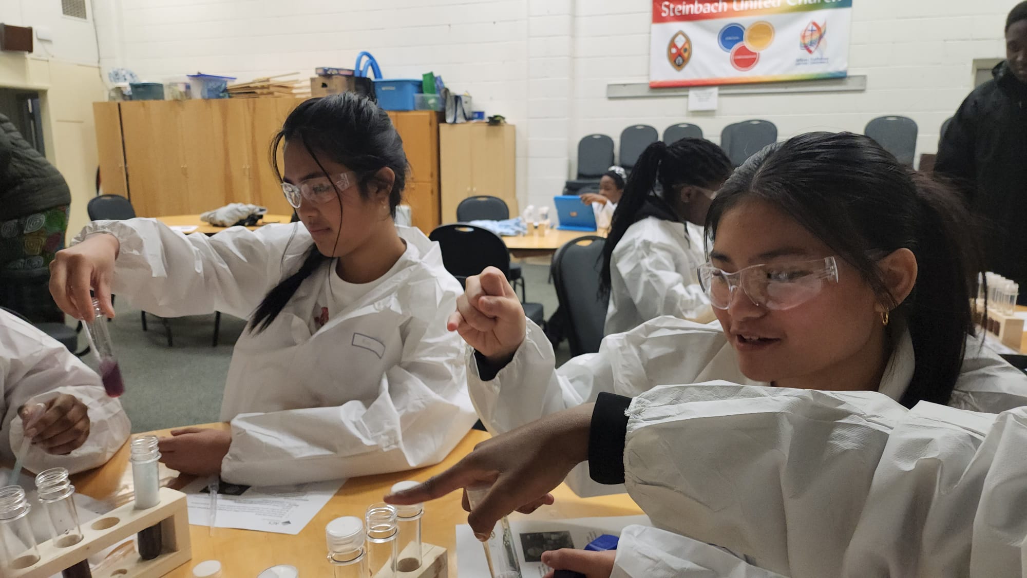 Participants examine liquid in test tubes at a workshop table